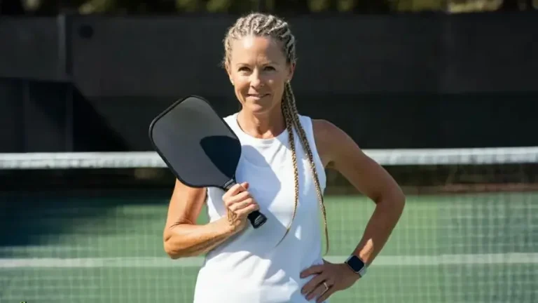 Confident female pickleball player holding paddle near net, representing mental toughness, confidence, and focus developed through strong pickleball psychology.