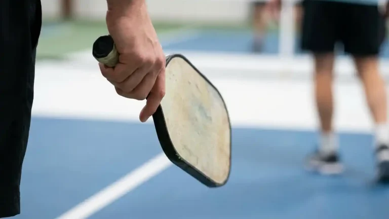 Close-up of a pickleball paddle held with a relaxed grip, illustrating the shift from a tight “death squeeze” to softer, more controlled hands during play.
